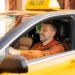 Motorista de táxi dirigindo veículo amarelo com identificação do programa Move Brasil, voltado à renovação da frota de transporte de passageiros.