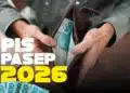 Homem segura carteira com notas de R$ 100, com destaque para PIS/Pasep 2026.