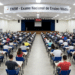 Centenas de estudantes fazem o Exame Nacional do Ensino Médio sentados em fileiras num auditório amplo.