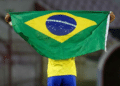 Atleta segurando a bandeira do Brasil em campo.