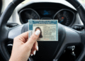 Pessoa exibe CNH dentro de carro moderno em destaque.