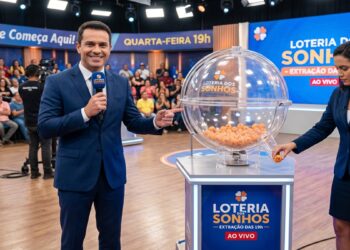 Apresentador sorri ao lado de globo de bolinhas e assistente exibe bola da Loteria dos Sonhos