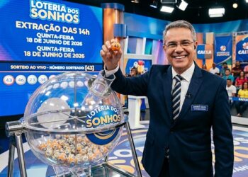 Apresentador segurando bola 43 no sorteio da Loteria dos Sonhos com painel e público ao fundo