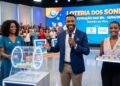 Três apresentadores da Loteria dos Sonhos mostram bolas sorteadas 19, 06, 26 e 08 em estúdio colorido