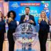 Quatro mulheres exibem bolas 18, 42, 07 e 65 ao lado de apresentador com microfone, cenário de Loteria dos Sonhos