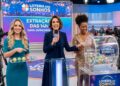 Três mulheres apresentam o resultado da Loteria dos Sonhos, segurando bolas e microfone ao vivo no estúdio