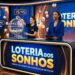 Duas mulheres apresentam o sorteio da Loteria dos Sonhos, uma operando o globo de bolas e outra lendo os resultados.