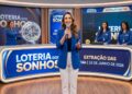 Apresentadora anuncia o resultado da Loteria dos Sonhos, com equipe feminina operando globos e números no estúdio azul