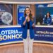 Apresentadora anuncia o resultado da Loteria dos Sonhos, com equipe feminina operando globos e números no estúdio azul