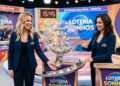Duas apresentadoras sorridentes com blazer azul realizam sorteio da Loteria dos Sonhos em estúdio colorido às 15h45