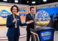 Mulher apresenta sorteio da Loteria dos Sonhos com microfone ao lado de globo com bolas amarelas