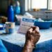 Pessoa idosa confere bilhete da Loteria dos Sonhos com números à mesa azul