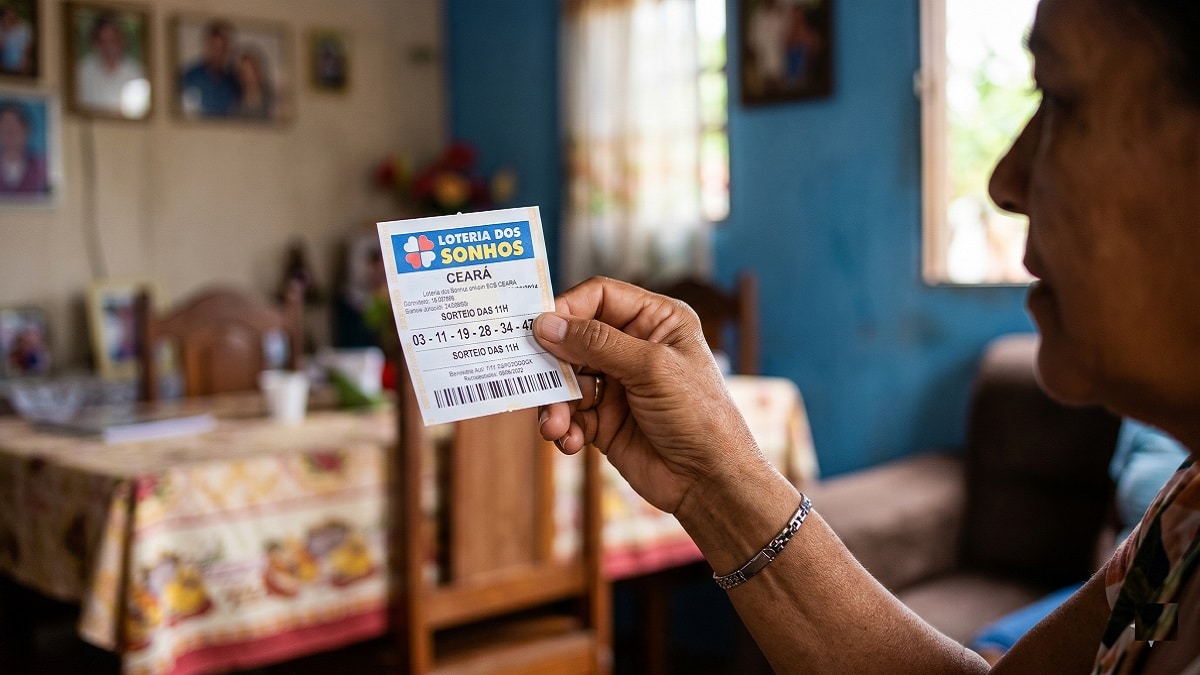 Mulher segurando bilhete da Loteria dos Sonhos Ceará em sala de casa decorada com fotos