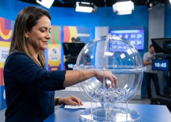 Apresentadora retira bola de globo transparente durante extração da Loteria dos Sonhos em estúdio de TV