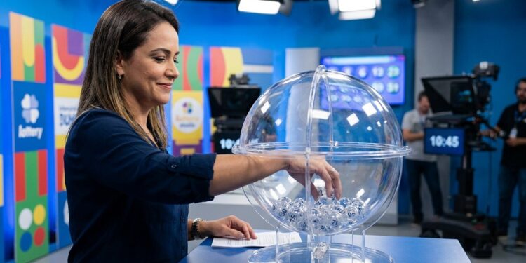 Apresentadora retira bola de globo transparente durante extração da Loteria dos Sonhos em estúdio de TV