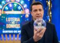 Homem de terno segura globo transparente com bola número 15 em estúdio da Loteria dos Sonhos