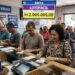 Grupo de pessoas preenchendo apostas da Lotofácil em lotérica da Caixa, com destaque para prêmio de 2 milhões