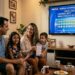Família reunida no sofá assistindo ao sorteio da Lotofácil 3710 na TV e sorrindo