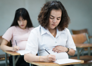 Mulheres grávidas realizando prova em sala de aula escolar.