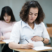 Mulheres grávidas realizando prova em sala de aula escolar.