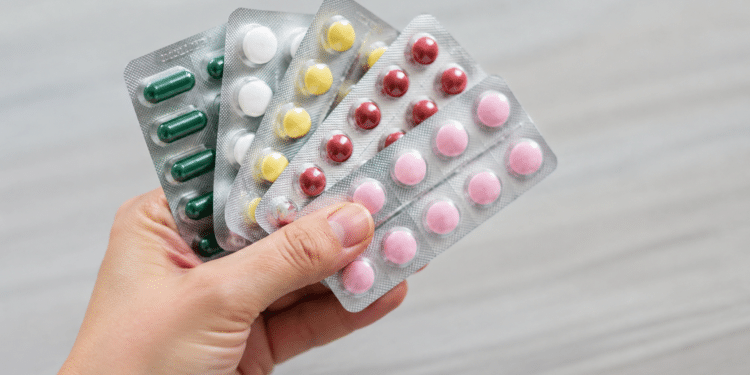 Cartelas de medicamentos seguradas por uma mão, ilustrando recolhimento de lotes pela Anvisa.