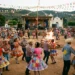 Festa junina em arraial com dança, fogueira, bandeirinhas e roupas típicas.