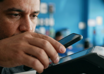 Homem aproxima o celular de uma maquininha para concluir um pagamento