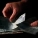 Mãos seguram notas de R$ 100 em imagem sobre pagamento do Auxílio Reconstrução pela Caixa.