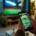Pessoa utilizando smartphone exibindo aplicativo de apostas, representando ações do governo contra bets ilegais e proteção de recursos públicos.