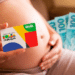 Gestante segura cartão do Programa Bolsa Família com logotipo colorido enquanto mostra notas de R$ 100 ao fundo