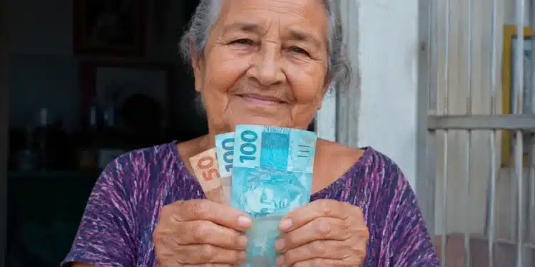 Idosa brasileira segurando dinheiro em espécie, representando a liberação de pagamentos do BPC nesta semana, entre 29/06 e 03/07.