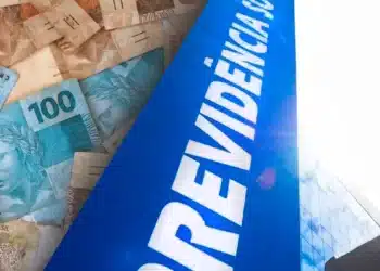Cédulas de real ao lado da fachada do prédio do INSS ilustrando o calendário de pagamentos do BPC em junho.