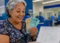 Aposentada sorrindo ao conferir cédulas de real em ambiente bancário, com calendário desfocado, ilustrando o pagamento do INSS de junho.