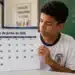 Estudante em sala de aula segurando calendário de junho de 2026, representando o cronograma de pagamentos do Pé-de-Meia deste mês.