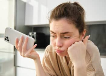 Mulher analisa o aparelho em dúvida sobre trocar ou consertar o celular