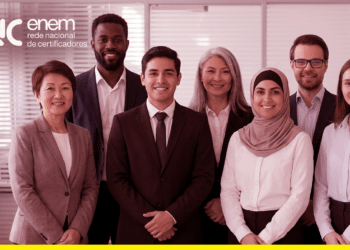 Equipe de profissionais sorridentes posa em ambiente corporativo ao lado da logomarca da Rede Nacional de Certificadores do Enem