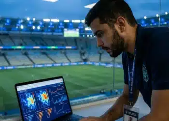 Analista de dados esportivos acompanhando métricas em tempo real em um estádio de futebol moderno.