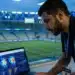 Analista de dados esportivos acompanhando métricas em tempo real em um estádio de futebol moderno.