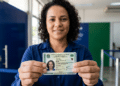 Mulher exibe a Carteira de Identidade Nacional em frente a um balcão de atendimento.