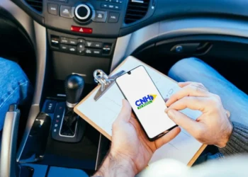 Candidato consulta informações da CNH pelo celular dentro de um carro durante processo de habilitação.