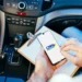 Candidato consulta informações da CNH pelo celular dentro de um carro durante processo de habilitação.