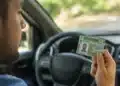 Motorista brasileiro segurando a CNH dentro de um carro moderno, destacando o documento e a mão do condutor, com interior desfocado ao fundo.