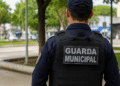 Guarda municipal de costas em ambiente urbano representando concurso público com vagas abertas.