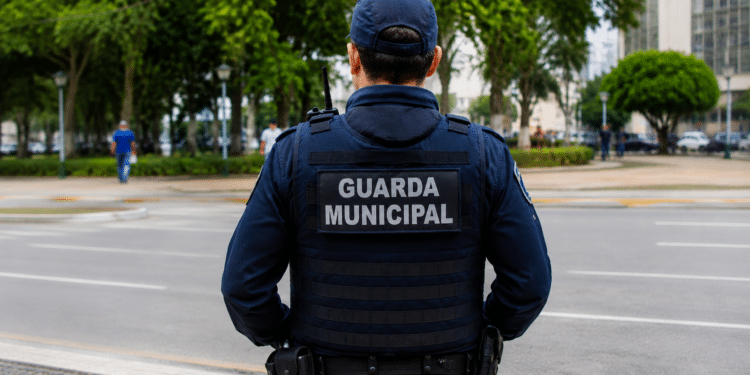 Agente da Guarda Municipal de costas em via pública durante patrulhamento.