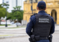 Guarda Municipal de costas com identificação no colete, representando concurso com 100 vagas e salário de até R$ 13.747,02.