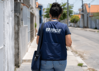 Profissional do IBGE caminha pela rua durante trabalho de campo.