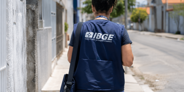 Profissional do IBGE caminha pela rua durante trabalho de campo.
