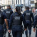 Grupo de policiais militares do Rio de Janeiro caminhando de costas em patrulhamento urbano.