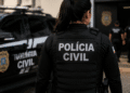 Policial civil de costas com viatura em operação.