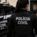 Policial civil de costas com viatura em operação.